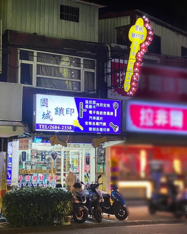 夜間點燈的國城鎖匙刻印店面，招牌與鑰匙造型霓虹燈亮著